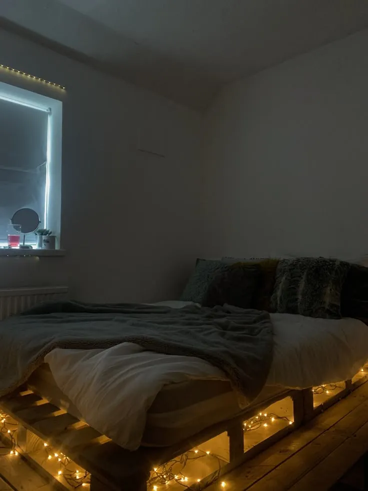 Pallet bed with warm string lights beneath the wooden base